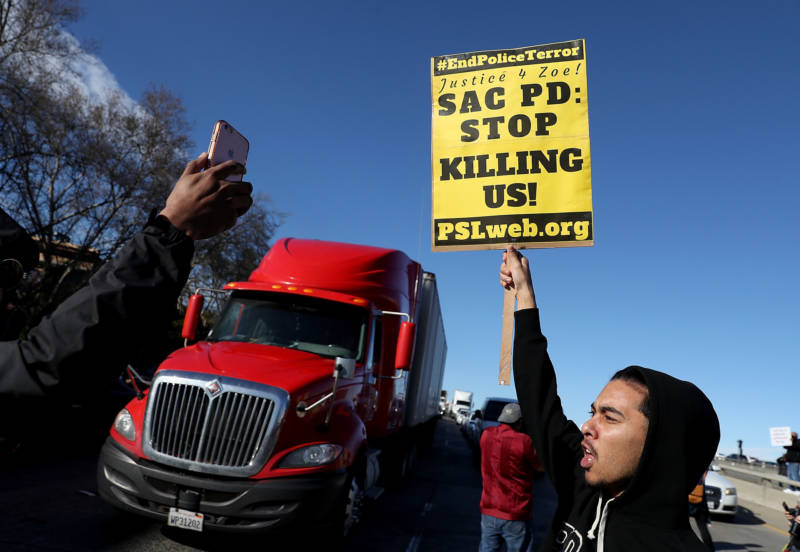 A Black Lives Matter protester holds a sign as he marches on Interstate 5 during a demonstration on March 22, 2018 in Sacramento.