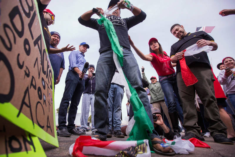 A pro-Trump demonstrator tears up a Mexican flag that was taken from a counter protester as supporters of President Donald Trump rallied during Trump's visit to see border wall prototypes on March 13, 2018 in San Diego.