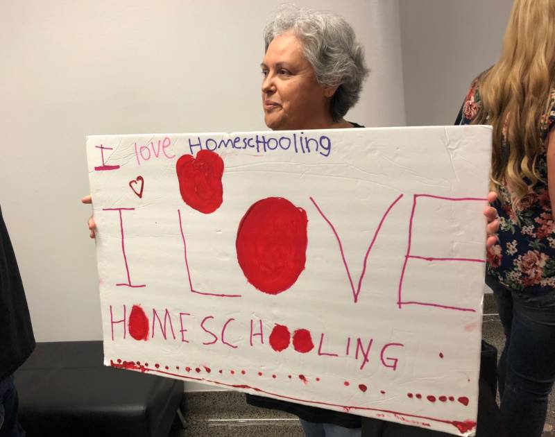 A woman holds a sign made by her grandchild while waiting for her turn to voice her opposition to a homeschool regulation bill.