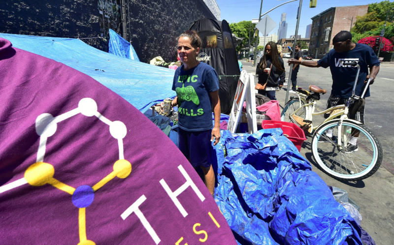 A homeless woman stands in front of her tent near Skid Row in downtown Los Angeles on June 20, 2017.