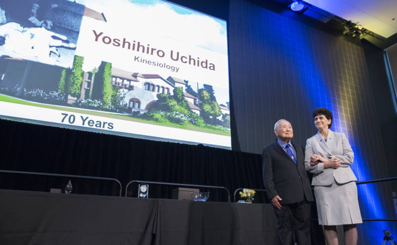 Coach Yoshihiro "Yosh" Uchida gets a standing ovation at the 2018 San Jose State Faculty Service Recognition and Awards Luncheon, with SJSU President Mary Papazian standing by his side.