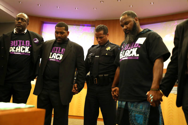 Sacramento police chief Daniel Hahn prays after Stevante Clark, brother of Stephon Clark, disrupted a special city council meeting at Sacramento City Hall on March 27, 2018.