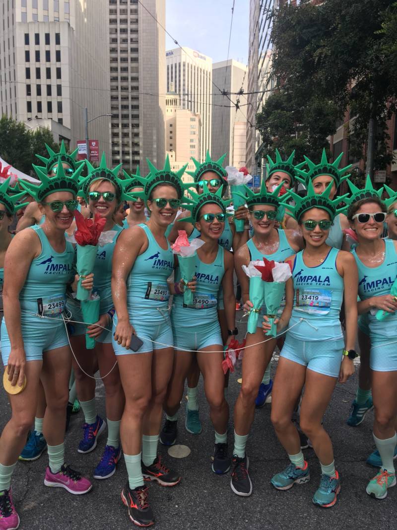 A team of runners wear coordinated Statue of Liberty costumes, complete with fake torches and matching running outfits. 