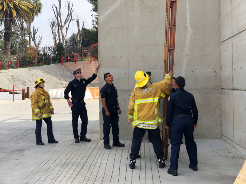 Firefighter trainers show candidates how to put up a heavy, 35-foot ladder.