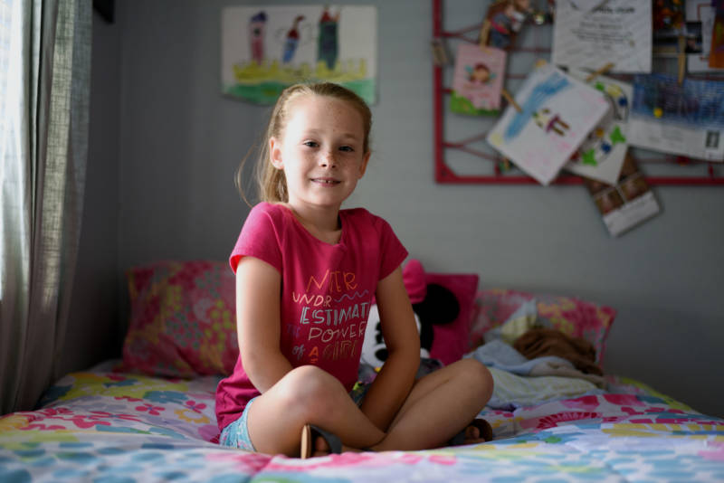Gracie (7) poses for a picture in her room surrounded by princess and Minnie Mouse imagery.
