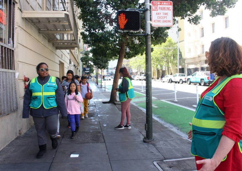 Kate Robinson (R) greets school children after Safe Passage volunteers cleared the Tenderloin sidewalk of people openly using drugs on April 24, 2018.