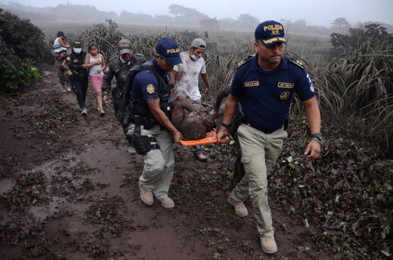 Police carry a wounded man after the eruption of the Fuego Volcano, in El Rodeo village, Escuintla department, on June 3, 2018.