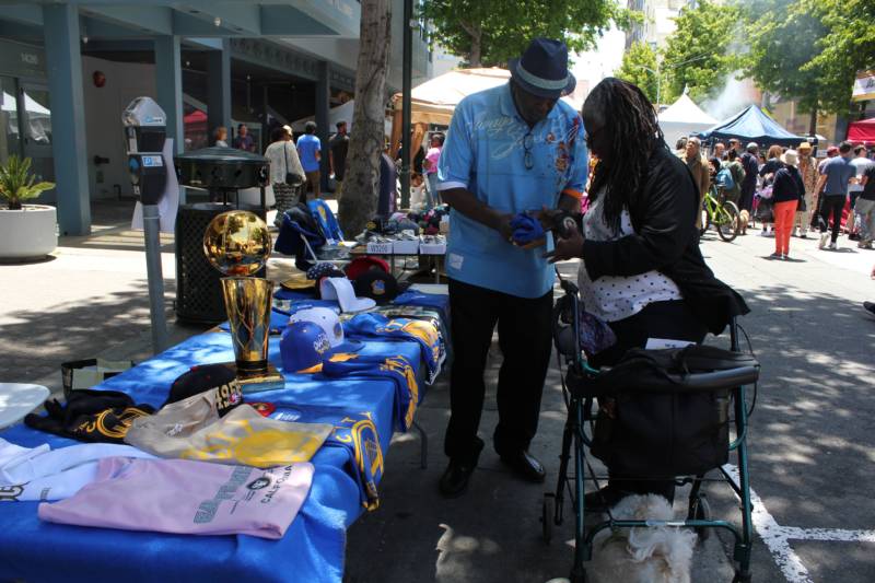Rodrick Jones of San Francisco selling a Warriors t-shirt to neighbor Dianne Jordan. They both say they've been coming to the festival for years.