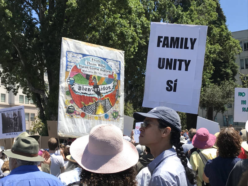 Just two of the many signs being carried at the 'Families Belong Together' rally in Berkeley.