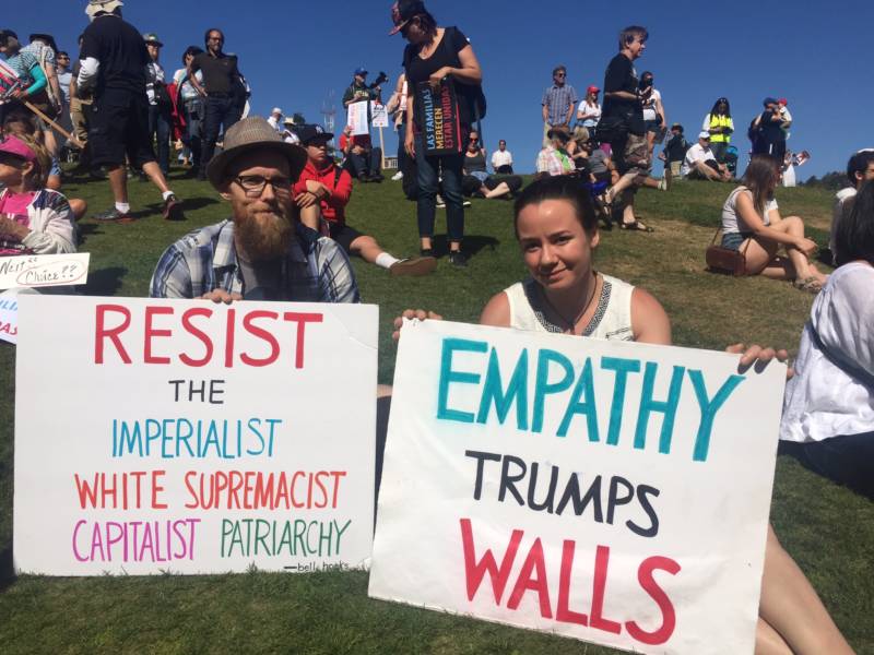 Dustin Ross (L) and Emily Claytor (R) both San Francisco residents, wait at Dolores Park to march in San Francisco's 'Families Belong Together' protest of family separation. Claytor says he doesn't have any concrete solutions for immigration reform, but he wants family separation to stop and the federal government to have more empathy.