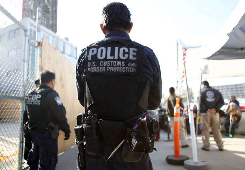 A U.S. Customs and Border Protection officer stands guard as pedestrians enter the United States at the San Ysidro port of entry.