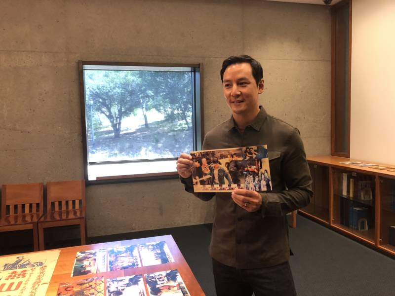 Daniel Wu holds up a poster of one of his films while touring the Fonoroff Collection at UC Berkeley's East Asian Library.
