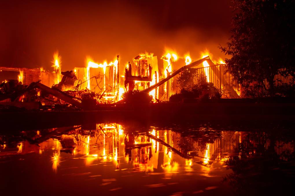 A burning home is reflected in a pool during the Carr fire in Redding, California on July 27, 2018.