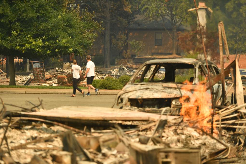 Residents walk through a burned neighborhood during the Carr fire in Redding, California on July 27, 2018.
