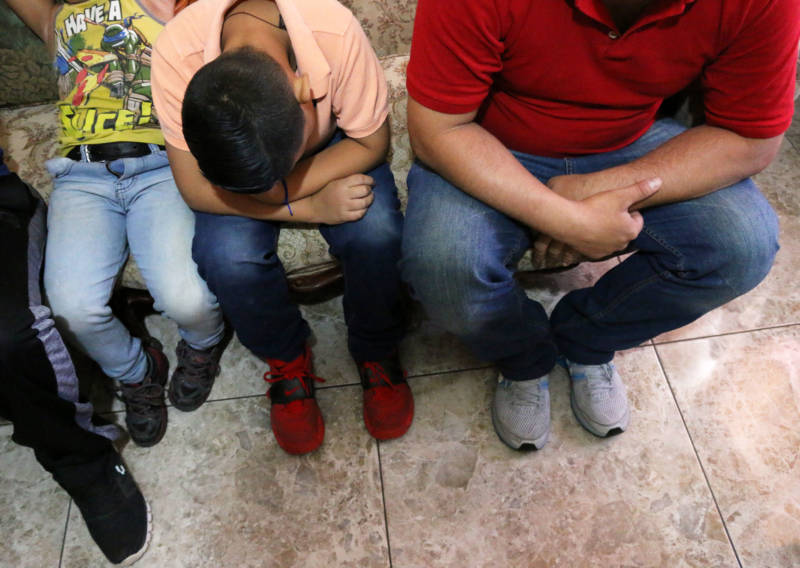 Elizabet’s husband and her two older sons wait in a family member’s living room in Mexico while they get ready to ask U.S. officials for asylum at the border.