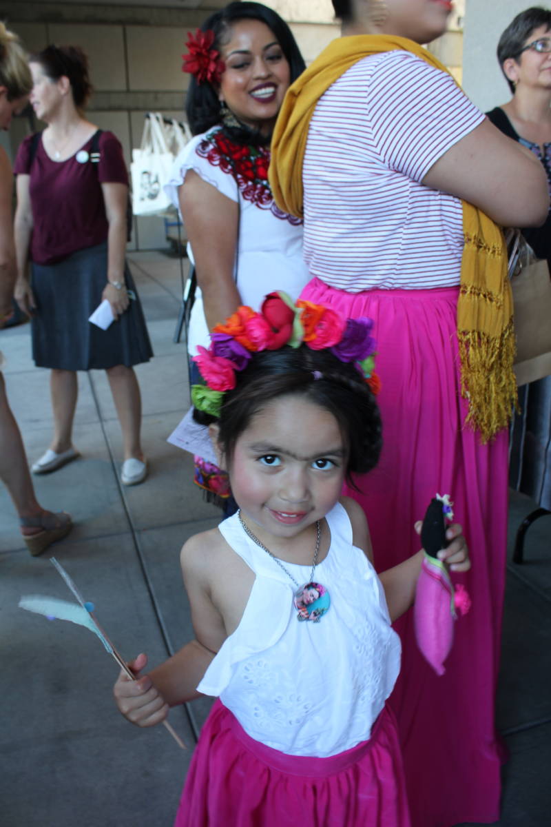 Gigi Orozco, 8-years-old, of San Francisco stands with her new Frida-inspired doll as her mother talks with a vendor at the Frida Kahlo event outside Bedford Gallery of Walnut Creek.