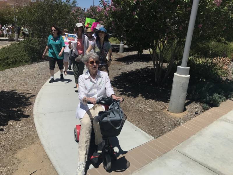 At 85, Judith Taylor organized and led her first protest against separated families. Taylor planned for about a dozen people to show up. Ultimately she led a march of 300 from her mobility scooter.