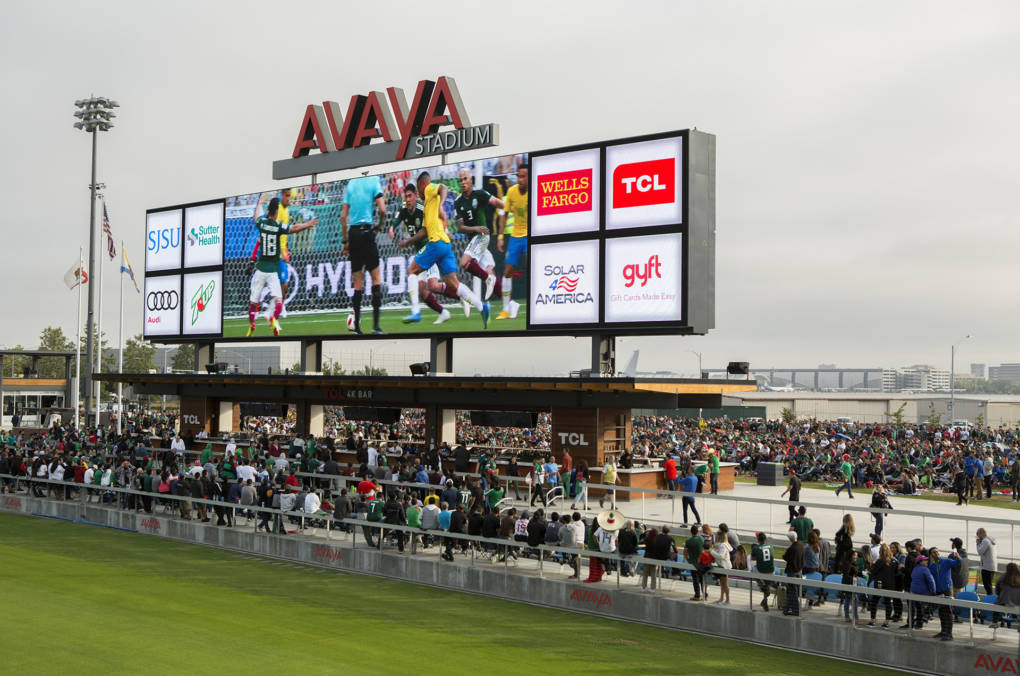 Fans crowded around both sides of the score board to watch the soccer match.