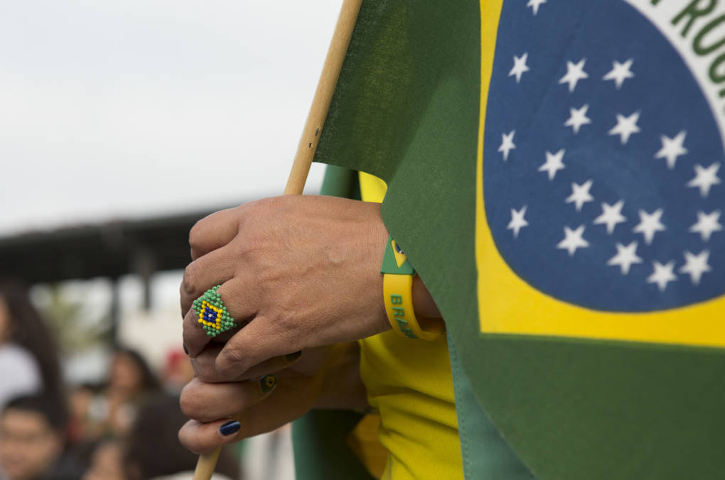 A Brazil fan sports a ring and a bracelet with the national colors while carrying a flag.