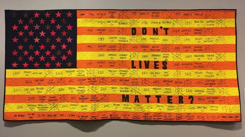 'Quilted Reimagined American Flag Series III: Don't Live Matter?' 2016 by Kelly Burke. The orange and yellow stripes signify caution. The 50 shades of red stars represent pain and suffering. Look closely and you can see the names of specific incidents written on the cloth.