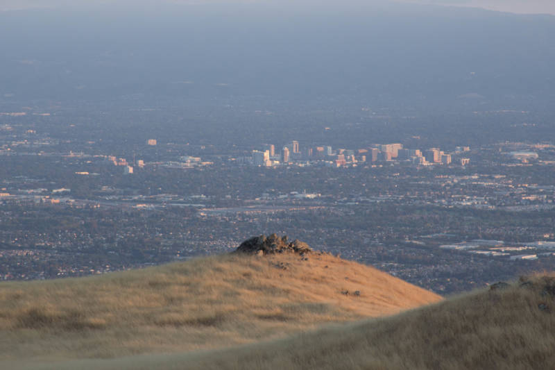 Downtown San Jose rises in the distance behind a small collection of stones seen from Monument Peak.