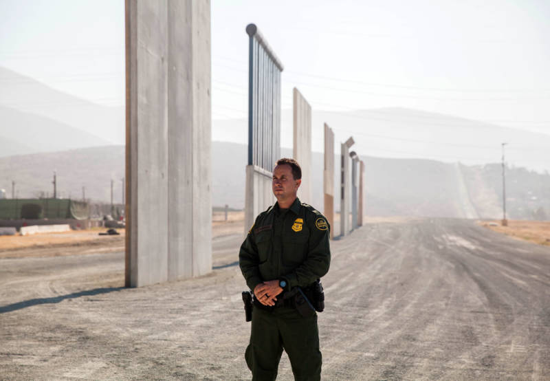 Theron Francisco, public affairs officer with the U.S. Border Patrol, stands in front of border wall prototypes in Otay Mesa.
