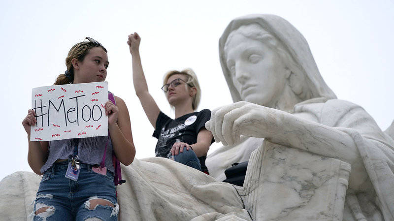 Protesters occupy the Contemplation of Justice statue in front of the U.S. Supreme Court Saturday after Judge Brett Kavanaugh was confirmed to the high court in a narrow Senate vote.