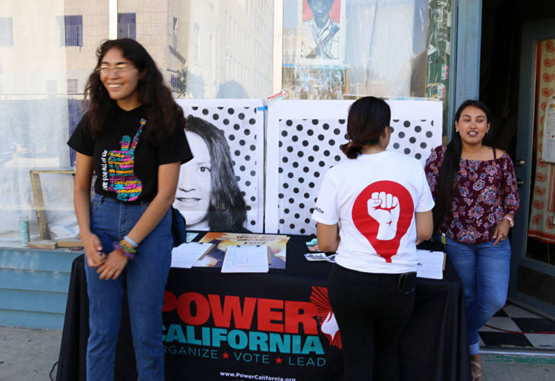 Valeria Mena (L) works the voter registration table at an art installation and Get Out the Vote event in downtown Fresno. Mena has been volunteering all summer to boost youth voter engagement in the Central Valley.