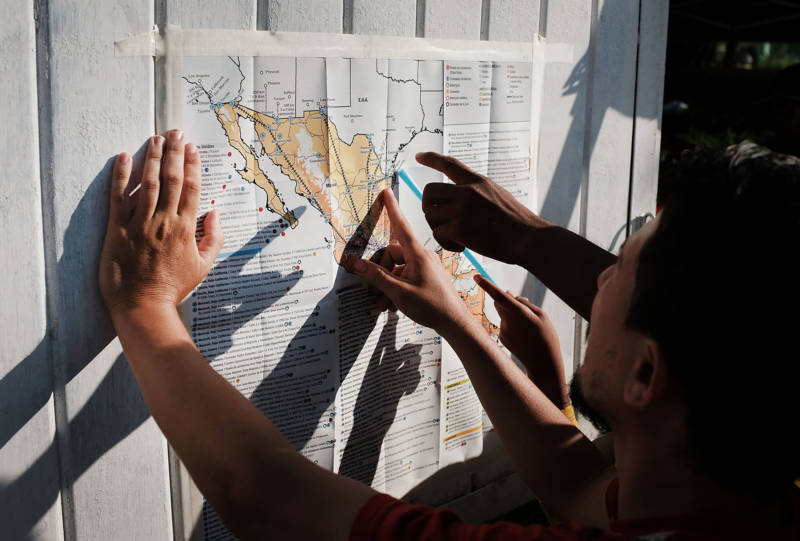Some of the thousands of Central American migrants look at a map after arriving into the small town of Santiago Niltepec, Mexico on Oct. 29, 2018.