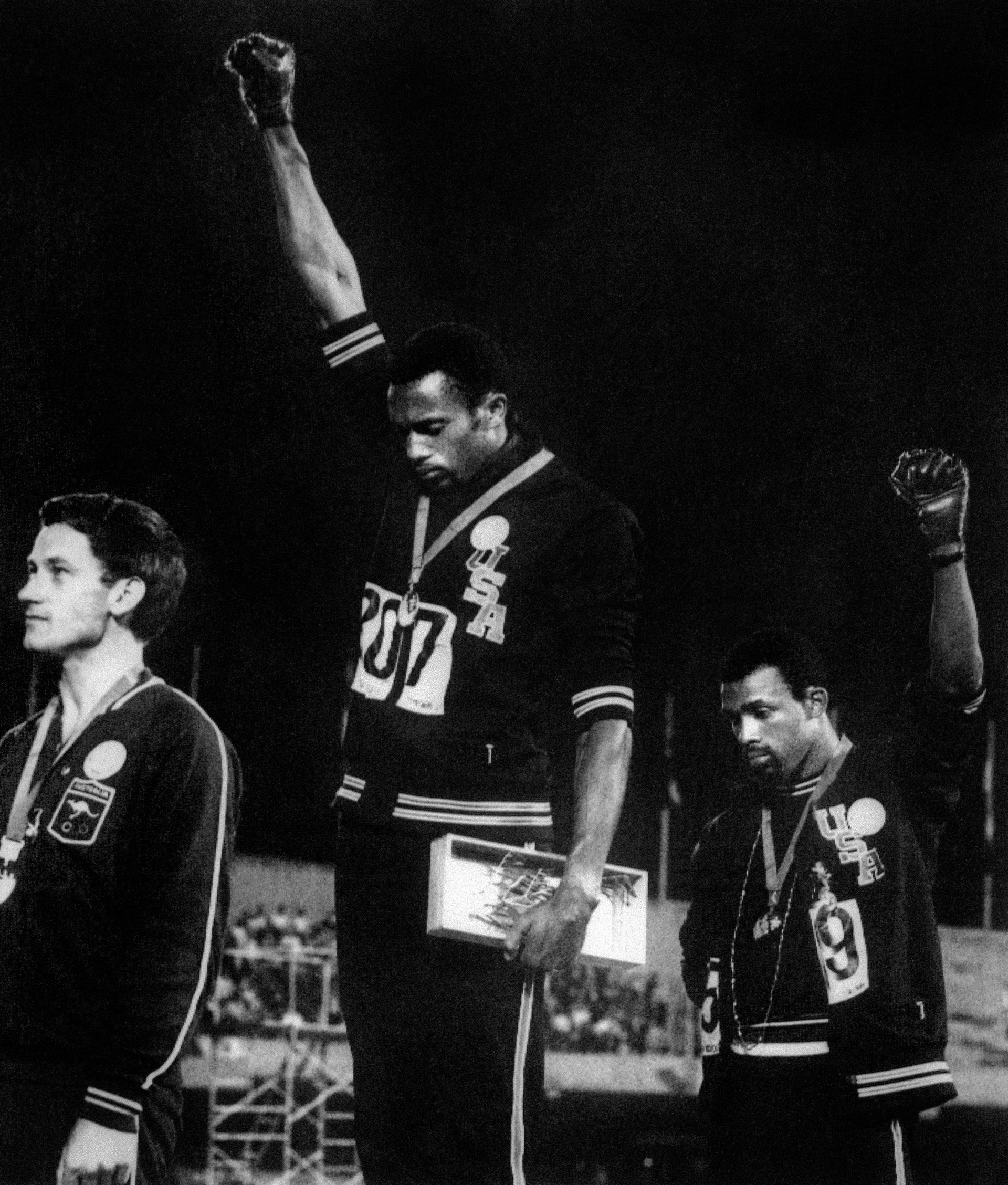 San Jose State University sprinter Tommie Smith, center, and John Carlos, right, raised their gloved fists on the awards podium at the 1968 Olympic Games in Mexico as a protest against racial oppression in America. Peter Norman of Australia, left, who took silver, wore an Olympic Project for Human Rights pin in solidarity.