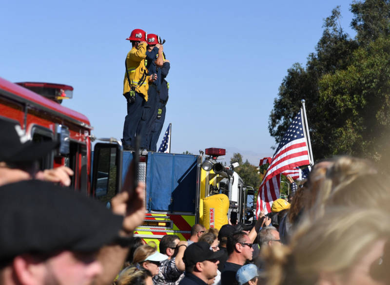 Firefighters salute as they watch a motorcade procession transporting the body of Sheriff's Sergeant Ron Helus on Nov. 8, 2018.