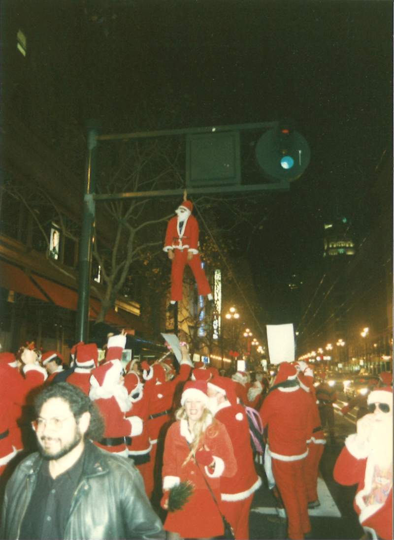 John Law hangs from a light wearing a harness underneath his suit.