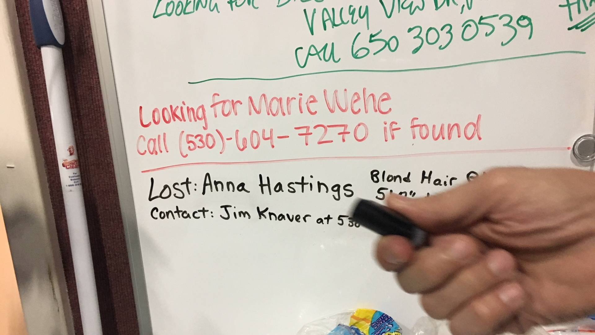 Jim Knaver adds the name of his wife, Anna, to a whiteboard at an evacuation center in Chico, Calif.