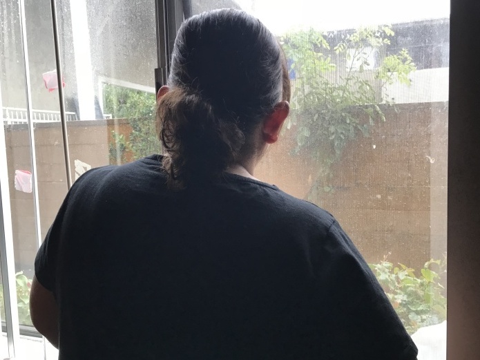 Lizeth, an immigrant from Honduras, looks out the window of her studio apartment in Los Angeles.