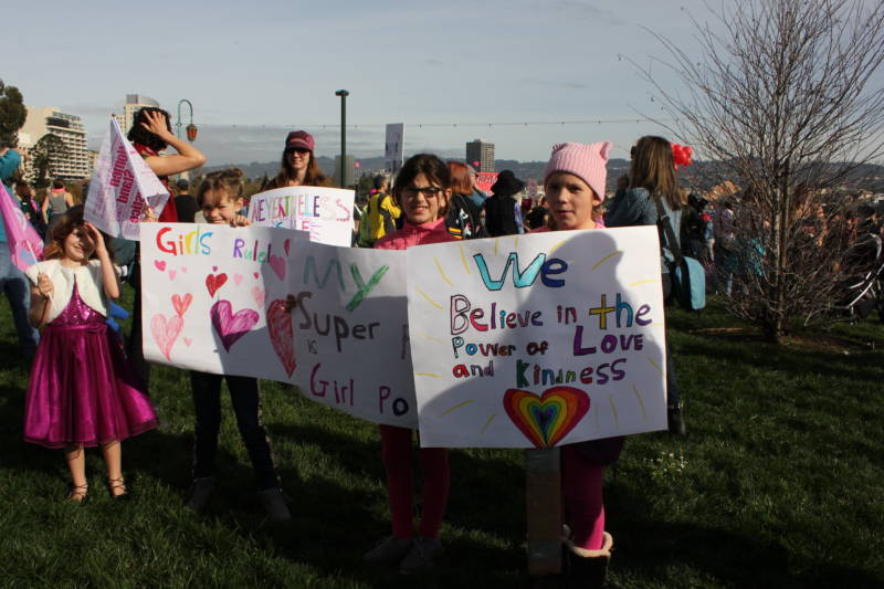 (L-R) Ashlyn Ferhart, 8; Sage White, 9; Poppy Henderson, 8; and Morgan Olsen, 9, all from West Marin, hold signs at the Oakland Women's March. The Power of Kindness sign was inspired by a song of the same name by MaMuse.