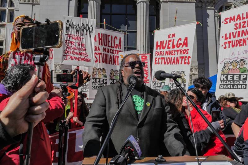 President of the Oakland Education Association teachers' union Keith Brown leads chant, “get up get down, Oakland is a union town” during a rally in front of city hall.