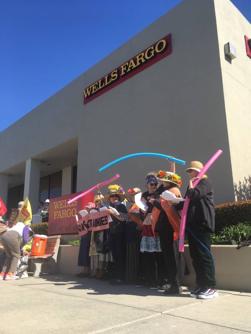 Protesters sing songs and flaunt pool toys outside of a Wells Fargo in San Carlos on March 16, 2019. They say the pool noodles represent preparation for sea level rise.