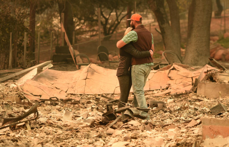 Chris and Nancy Brown embrace while looking over the remains of their burned residence after the Camp fire tore through the region in Paradise, California on November 12, 2018.