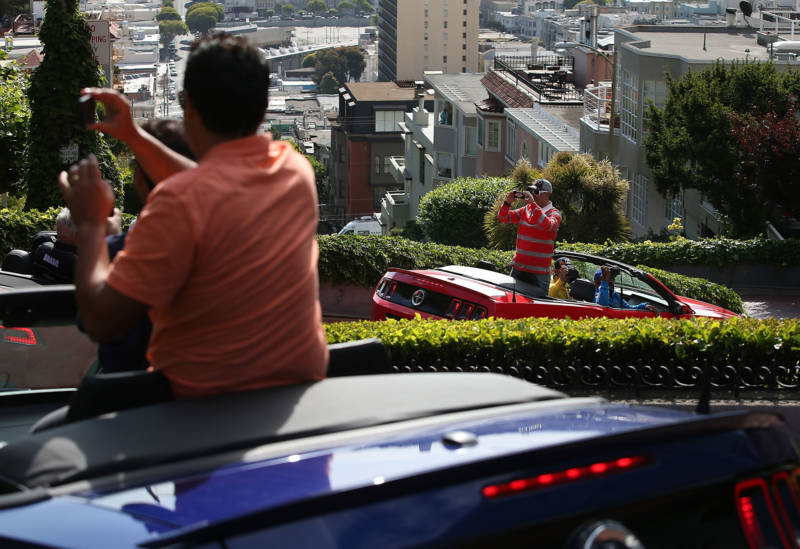 Tourists take photos while driving down Lombard Street on May 20, 2014 in San Francisco.