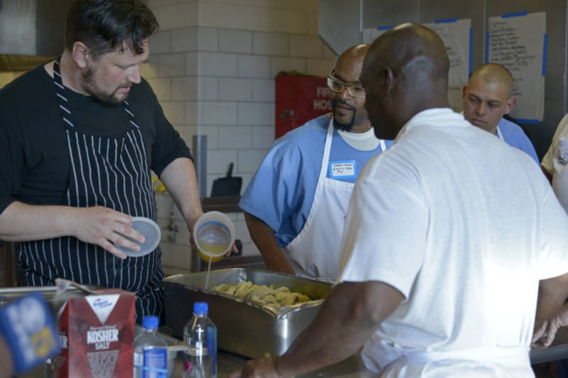 Chef Huw Taylor (left) helps students prepare food for the fifth Quentin Cooks graduation dinner at San Quentin State Prison on May 22, 2019.