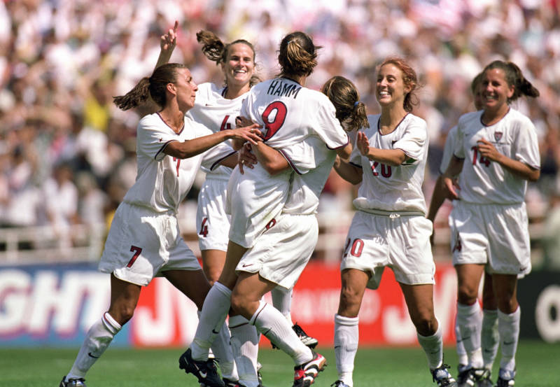 Mia Hamm #9 of Team USA is embraced by Shannon MacMillan #8 as teammates Joy Fawcett #14, Kate Sobrero #20, Carla Overbeck #4 and Sara Whalen #7 celebrate the victory over Team China in the Final match of the FIFA Women's World Cup at the Rose Bowl on July 10, 1999 in Pasadena, California. It was the team's second World Cup championship in three tournaments and one of three its won since 1991.
