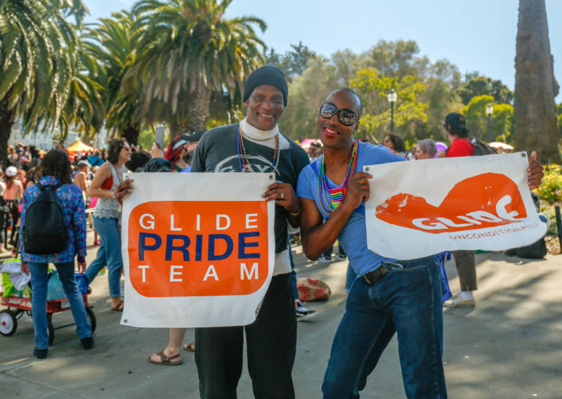 Two men hols banners that say "Glide Pride Team."