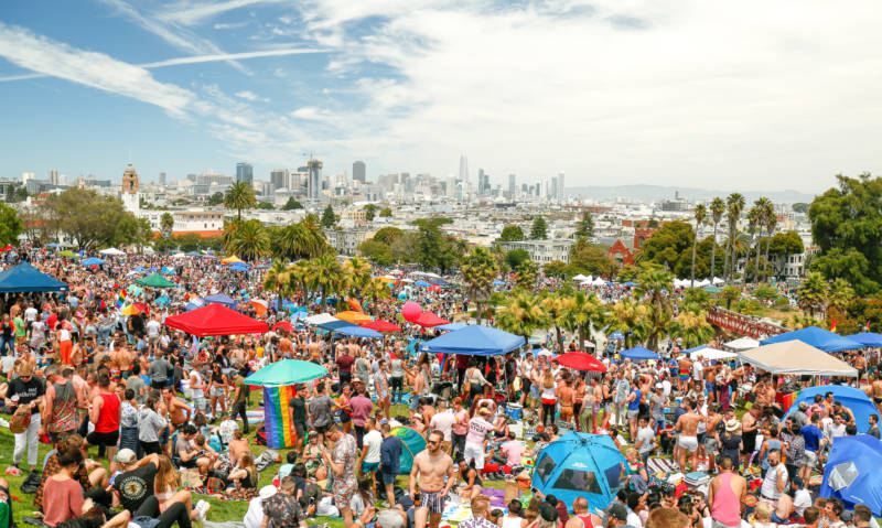 Thousands of people gather at Dolores Park on a beautiful sunny day. Picture looks like something out of a movie. 