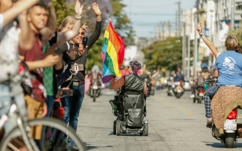 A person rolls down the parade in their electric wheelchair. 