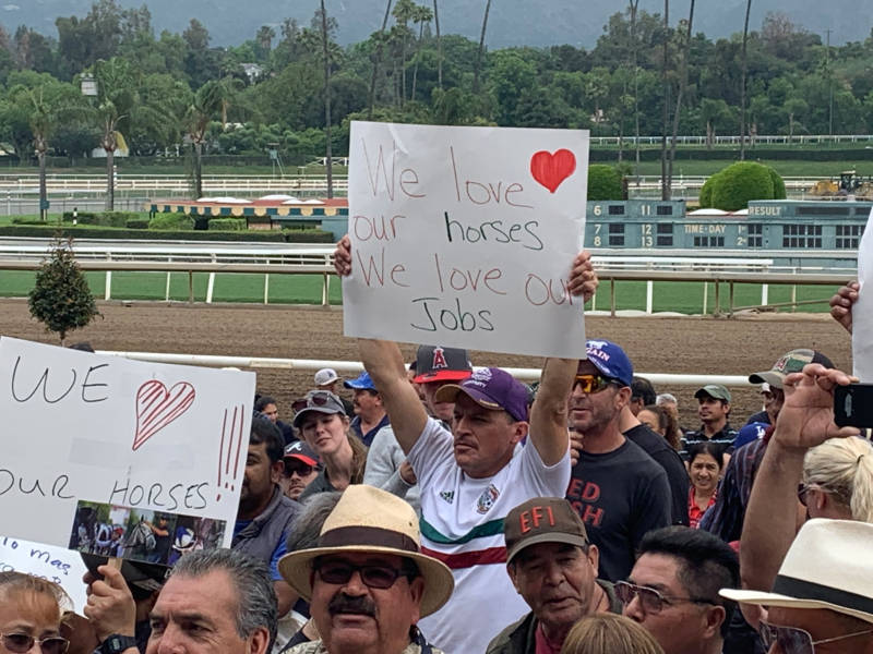 A Santa Anita Park worker holds up a sign of support at the track on June 20, 2019.