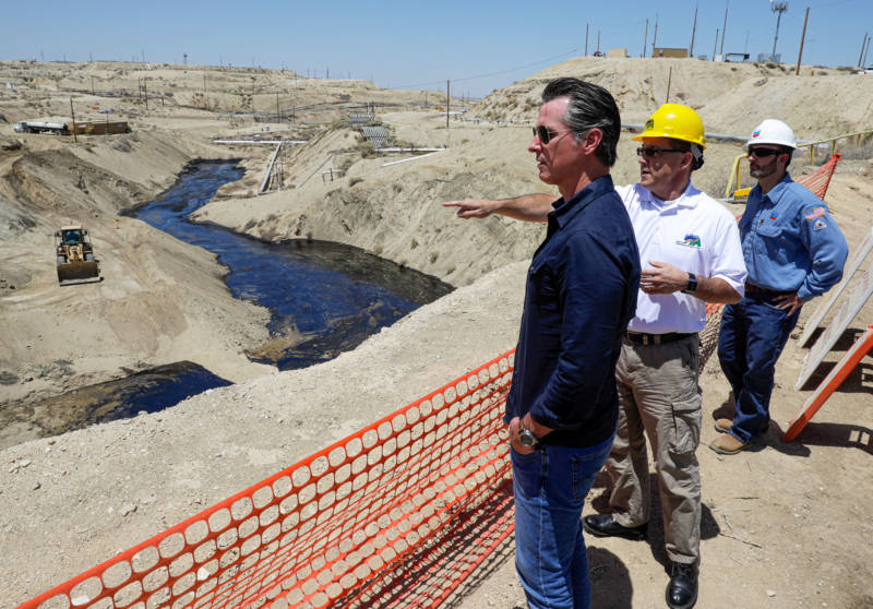 Gov. Gavin Newsom is briefed by Billy Lacobie, of Chevron (right), and Jason Marshall (center), acting supervisor of the state Division of Oil, Gas and Geothermal Resources (DOGGR) on Wednesday while touring the Chevron oil field near Bakersfield where a spill of at least 974,400 gallons of fluid have flowed into a dry creek bed.