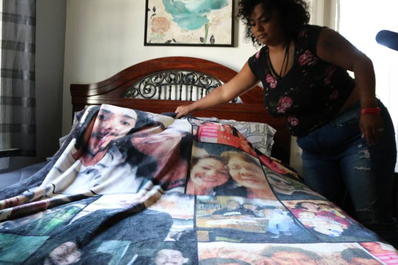Alicia Saddler lays out a blanket with photos of her brother, Angel Ramos, and their mother.