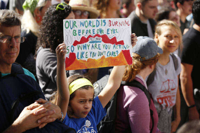 Natali, 10, holds high a sign reading, "Our world is burning before our eyes, so why are you acting like you don't care?" in front of House Speaker Nancy Pelosi's office during a youth-led climate march on Sept. 20, 2019.