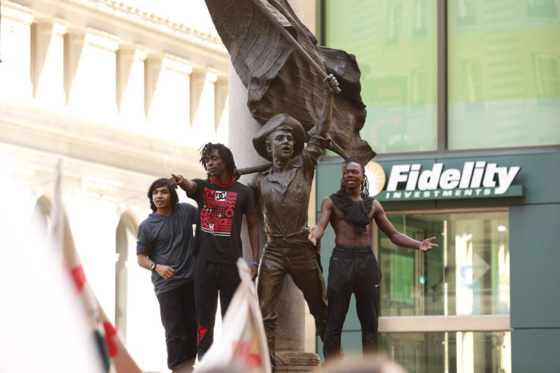 Oakland Tech High School students (L-R) Nikko Cabrera, Keeto Gaines, and Mazi Wyatt stand on the Admission Day Monument on Market Street during a youth-led climate march, Sept. 20, 2019. The three said they jumped up on the statue because they felt inspired by the crowd.