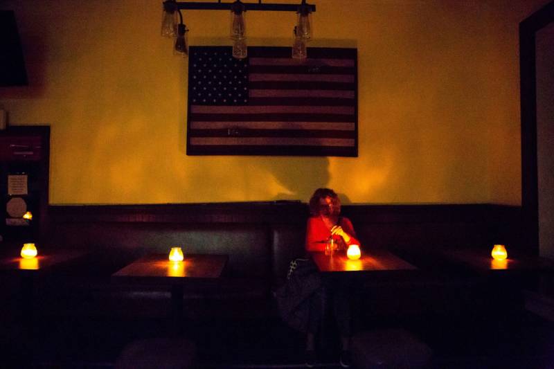Judy Aquiline, a Sonoma local, sits in the candle-lit restaurant Reel and Brand in Sonoma on Oct. 9, 2019, during a planned power outage by the Pacific Gas & Electric utility company.